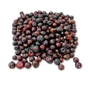 May include: A close-up of a pile of dried juniper berries. The berries are dark purple and black in color and have a slightly wrinkled texture.