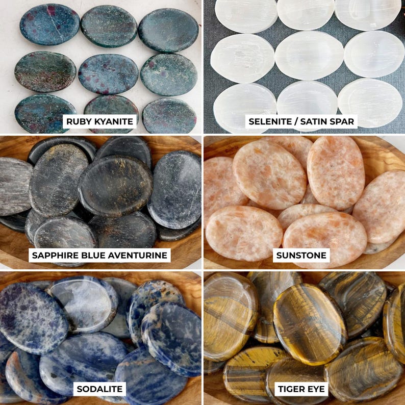 May include: A collection of polished gemstones, including Ruby Kyanite, Selenite/Satin Spar, Sapphire Blue Aventurine, Sunstone, Sodalite, and Tiger Eye. Each stone is oval-shaped and displayed in wooden bowls. Text labels identify each stone type.