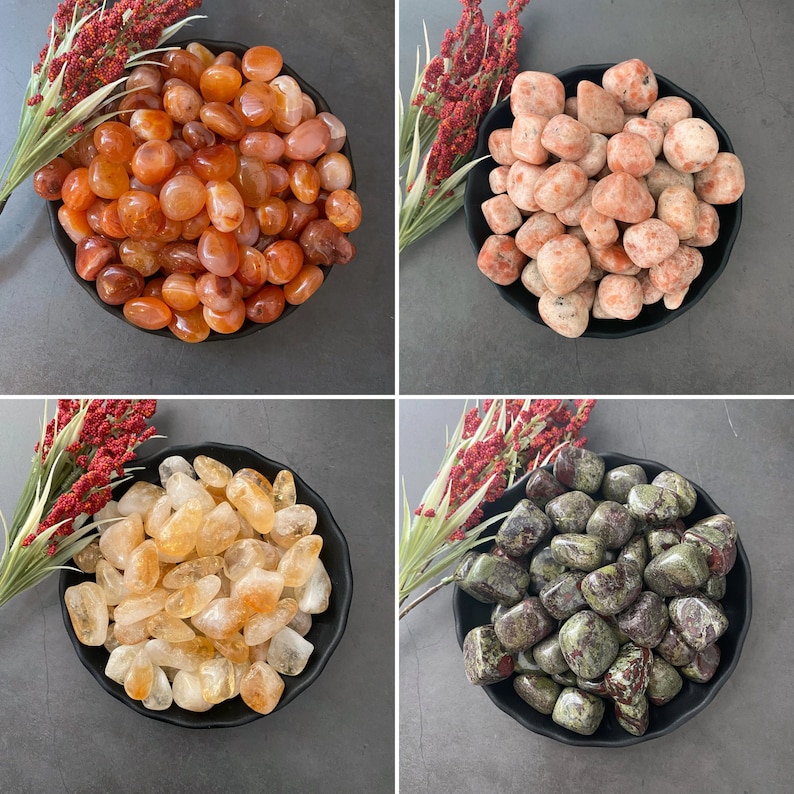 May include: Four bowls of tumbled stones, each bowl containing a different type of stone. The bowls are black and the stones are various colors, including red, orange, yellow, green, and brown.