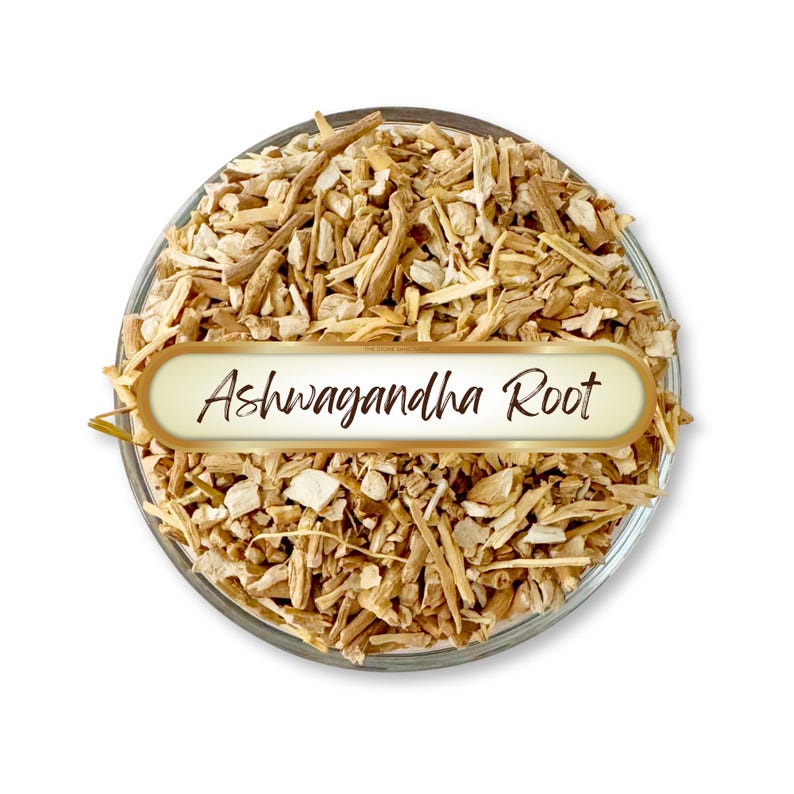 May include: A clear glass bowl filled with chopped ashwagandha root. The root pieces are light brown and beige. A gold-edged label with the words "Ashwagandha Root" is placed over the root.