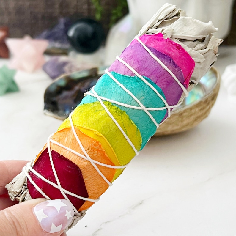 May include: A rainbow smudge stick with white sage and dried rose petals in red, orange, yellow, green, blue, purple and pink.