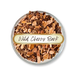 May include: A clear glass bowl filled with wild cherry bark. The bark pieces are various shades of brown and tan. A gold-edged label with the words "Wild Cherry Bark" is centered in the bowl.