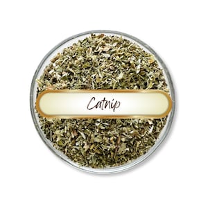 May include: A clear glass bowl filled with dried catnip. The catnip is a mix of green and brown, with a label that reads "Catnip" in a cursive font. The bowl is set against a white background.