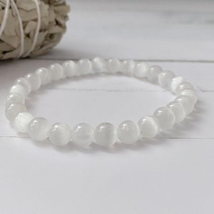 Peut inclure: Bracelet en perles de pierre de lune blanche. Le bracelet est compos&eacute; de petites perles rondes enfil&eacute;es sur un cordon &eacute;lastique transparent.
