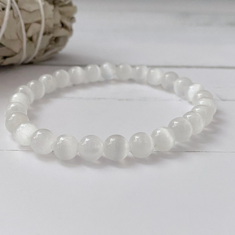 Peut inclure: Bracelet en perles de pierre de lune blanche. Le bracelet est compos&eacute; de petites perles rondes enfil&eacute;es sur un cordon &eacute;lastique transparent.