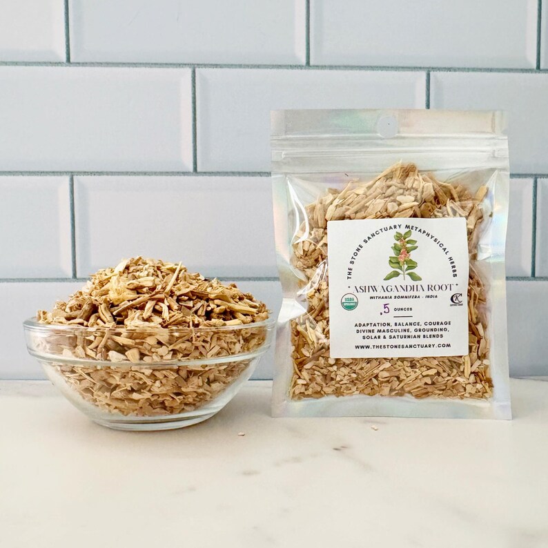 May include: A clear glass bowl filled with chopped, light brown ashwagandha root sits next to a clear plastic bag of the same. The bag has a label with text including "ASHWAGANDHA ROOT" and "5 ounces".