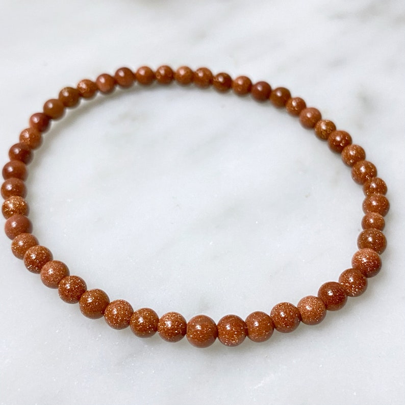 May include: A brown beaded bracelet made of small, round, speckled stones.