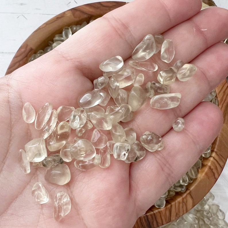 Puede incluir: Un pu&ntilde;ado de peque&ntilde;as piedras de citrino pulidas, transparentes y lisas. Las piedras son de color amarillo claro.
