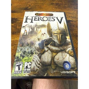 May include: A PC video game case for Might and Magic Heroes V featuring a knight in white and gold armor with winged helmet. The cover art displays a fantasy castle, a battlefield scene, the Ubisoft logo, and an ESRB Teen rating symbol.