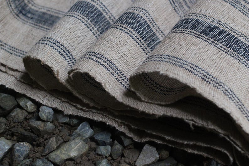 May include: Close-up of a folded piece of fabric with blue and white stripes. The fabric is woven and has a rough texture. The fabric is folded in a way that shows the different layers.