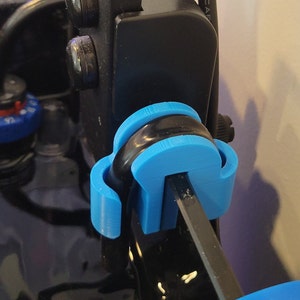 May include: A close-up of a blue 3D printed part attached to a black metal rod. The part is designed to hold the rod in place.