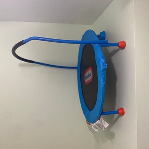 May include: A blue and black Little Tikes trampoline with a red handle and red legs. The trampoline is mounted on a wall.