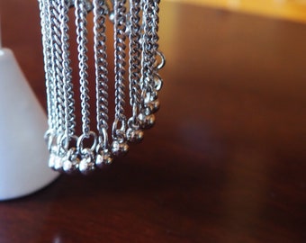 May include: A silver chain necklace with multiple strands and small silver beads at the ends.