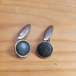 Puede incluir: Un par de gemelos de plata con piedras redondas de color verde oscuro.