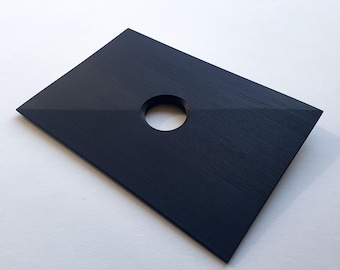 May include: A black rectangular wooden plaque with a circular hole in the center. The plaque has a wood grain texture.