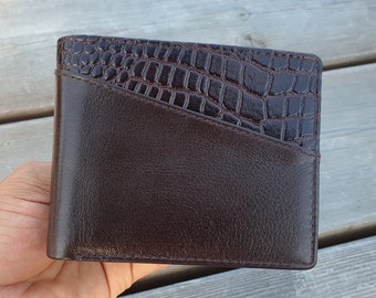 May include: A brown leather wallet with a crocodile-embossed design on the front flap.