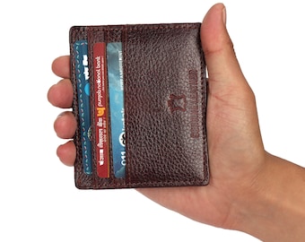 May include: A brown leather wallet with a card slot and the text "GENUINE LEATHER" embossed on the front. The wallet is being held in a hand.