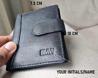 May include: Black leather wallet with a BMW logo, measuring 7.5 inches by 10 inches. The wallet has a flap with a snap closure.