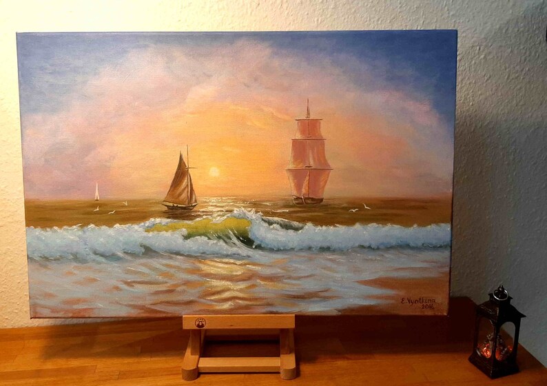 May include: A painting of two sailboats on a calm sea at sunset. The sky is a mix of pink, orange, and blue, with fluffy clouds. The water is a deep blue, with whitecaps and a golden reflection of the sun. The painting is signed "Z. Wantling 2018" in the lower right corner.