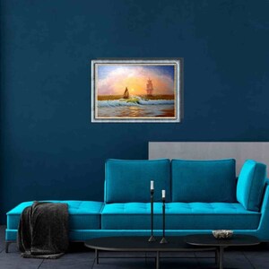 May include: A framed painting of a sailboat on the ocean with a larger ship in the distance. The painting is set against a blue wall with a teal couch in front of it.