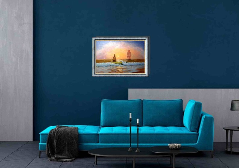 May include: A framed painting of a sailboat on the ocean with a larger ship in the distance. The painting is set against a blue wall with a teal couch in front of it.