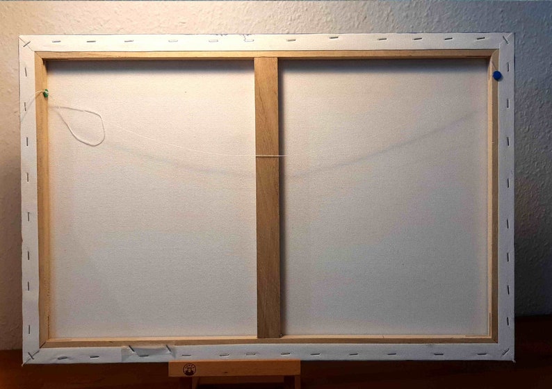 May include: The back of a stretched canvas painting with a wooden frame. The canvas is white and has a string attached to it for hanging.