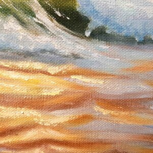 May include: A close-up of a painting depicting a sandy beach with waves crashing on the shore. The painting is done in a realistic style with a focus on the texture of the sand and the water.