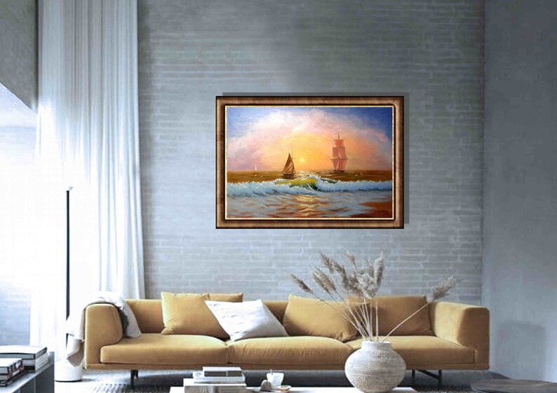 May include: A painting of a seascape with two sailboats on the water. The sky is a soft pink and orange, and the water is a deep blue. The painting is framed in a brown frame.