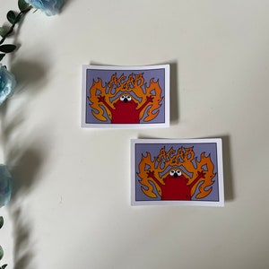 May include: Two stickers featuring a red cartoon character with large eyes, surrounded by orange flames, with the text "ACAB" in the flames. The stickers are on a white background.