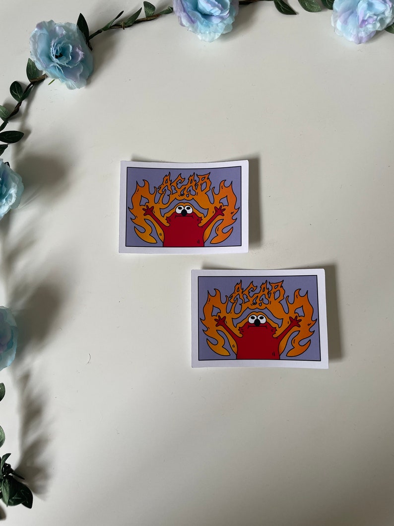 May include: Two stickers featuring a red cartoon character with large eyes, surrounded by orange flames, with the text "ACAB" in the flames. The stickers are on a white background.