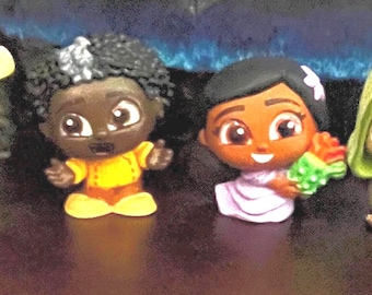 May include: Set of seven small, colorful figurines of cartoon characters. The characters are all wearing different outfits and have large eyes.