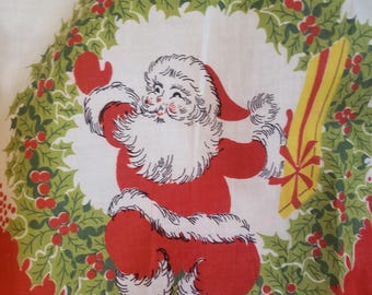 May include: A vintage Christmas tablecloth featuring a cheerful Santa Claus design. Santa is depicted in a red suit with white trim, holding a gift. The design is set against a white background, framed by a wreath of green holly and red berries.