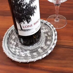 May include: A bottle of Lone Birch Red Blend wine from 2014, sitting on a gray and white coaster. Two clear wine glasses are on a wooden table.