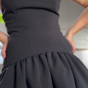 Puede incluir: Un vestido negro sin tirantes con un corpiño ajustado y una falda con volantes.