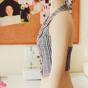 View of the vest from the side. You can see that the vest is held on the neck with a collar.
The shoulders are completely open.The vest is worn over the head on the neck.