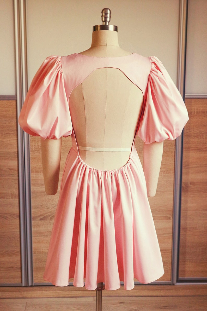 The dress is sewn from peach colored satin coarse fabric.Full length back view.Knee-length skirt