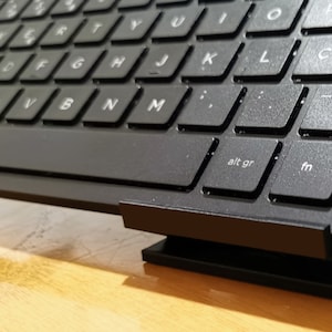 Peut inclure: Un clavier noir avec une touche argentée intitulée "alt gr" et une autre touche intitulée "fn".