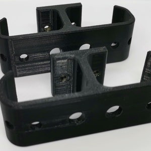 Puede incluir: Dos soportes negros impresos en 3D con varios agujeros. Los soportes est&aacute;n dise&ntilde;ados para montarse en una pared u otra superficie.