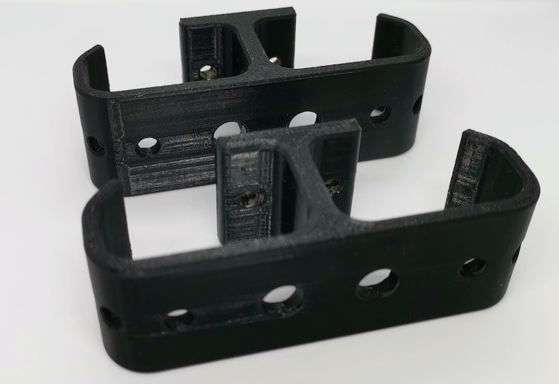 Puede incluir: Dos soportes negros impresos en 3D con varios agujeros. Los soportes est&aacute;n dise&ntilde;ados para montarse en una pared u otra superficie.