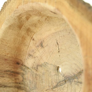 May include: A close-up of the inside of a wooden bowl, showing the natural grain of the wood and a small hole in the center.