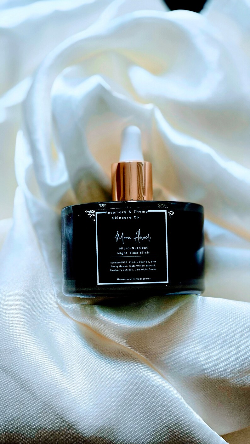 May include: A black glass bottle with a white dropper cap and a square label. The label reads Rosemary & Thyme Skincare Co., Moon Flower, Micro-Nutrient Night Time Elixir, and lists ingredients including Prickly Pear oil, Blue Tansy flower, and Watermelon extract.