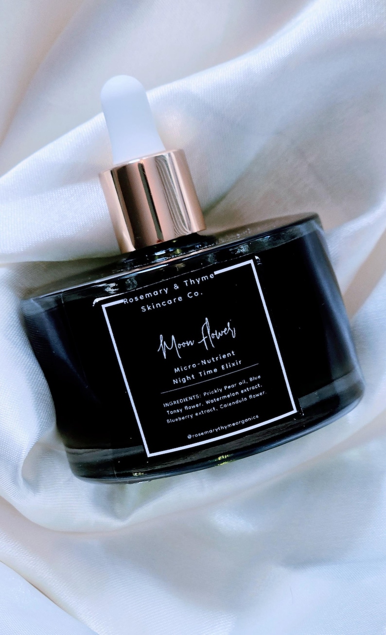 May include: A black glass bottle with a white dropper top, featuring a square label that reads Rosemary & Thyme Skincare Co. Moon Flower Micro-Nutrient Night Time Elixir, listing ingredients including Prickly Pear oil and Blue Tansy flower.