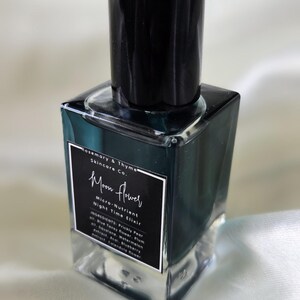 May include: A square glass bottle containing a dark teal liquid with a black cap. The label reads Rosemary & Thyme Skincare Co. Moon Flower Micro-Nutrient Night Time Elixir, listing ingredients including Prickly Pear oil, Blue Tansy flower, and Plum oil.