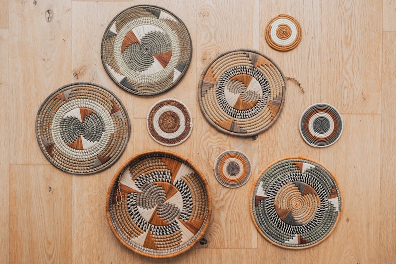 May include: A set of seven woven wall decor pieces in various sizes and patterns. The pieces are made of natural materials and feature a variety of colors, including brown, beige, and green.