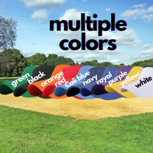 May include: A row of ten baseball caps in different colors, including green, black, orange, red, blue, navy, royal, purple, yellow, and white. The caps are arranged in a line on a grassy surface with the words "multiple colors" above them.