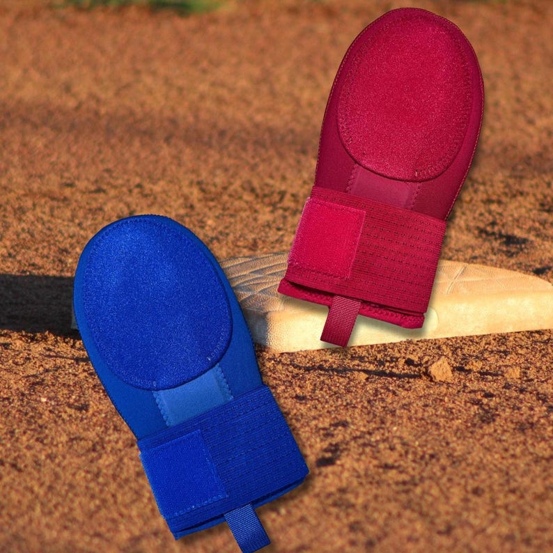Puede incluir: Dos guantes de b&eacute;isbol, uno rojo y otro azul, se muestran en un campo de b&eacute;isbol. Cada guante tiene una parte superior ovalada acolchada y una correa para la mu&ntilde;eca con cierre de velcro. Los guantes est&aacute;n dise&ntilde;ados para proteger las manos al batear.