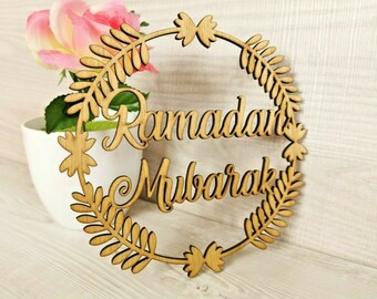 May include: Wooden sign with a floral wreath design and the text "Ramadan Mubarak".