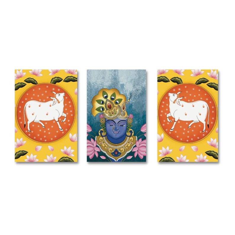 Puede incluir: Un conjunto de tres impresiones enmarcadas que representan una deidad hind&uacute; con una corona de plumas de pavo real, una vaca blanca y un fondo amarillo con flores de loto rosas.
