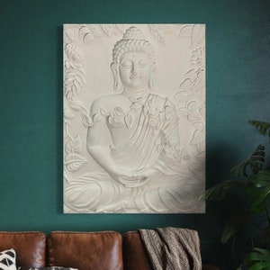 May include: White 3D wall art featuring a Buddha sculpture with floral details. The sculpture is set against a white background and is surrounded by intricate floral designs.