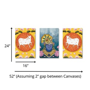 Puede incluir: Un conjunto de tres impresiones sobre lienzo de 40,6 x 61 cm que representan deidades hind&uacute;es. La impresi&oacute;n central representa una deidad de piel azul con una corona dorada y plumas de pavo real. Las impresiones de la izquierda y la derecha presentan una vaca blanca sobre un fondo rojo y naranja.